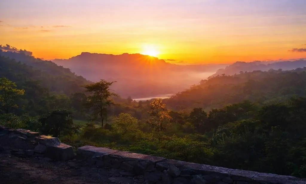 Sunrise over mistly forest valley and distant hills